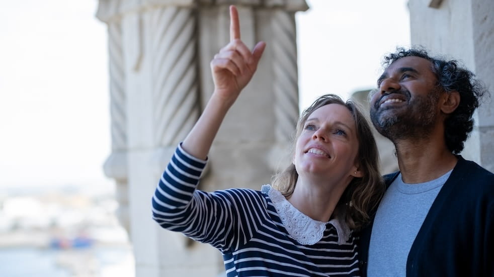 Couple on holiday with woman pointing out something high up